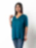 A woman wearing a teal V-neck top with lace shoulder details, paired with jeans on a white background, showcasing a stylish casual look.
