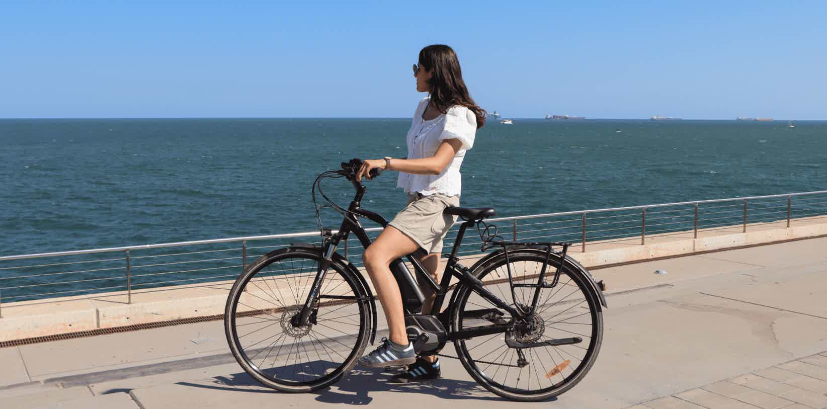 mujer usando bicicleta electrica en barceloneta playa verano barcelona españa ebike