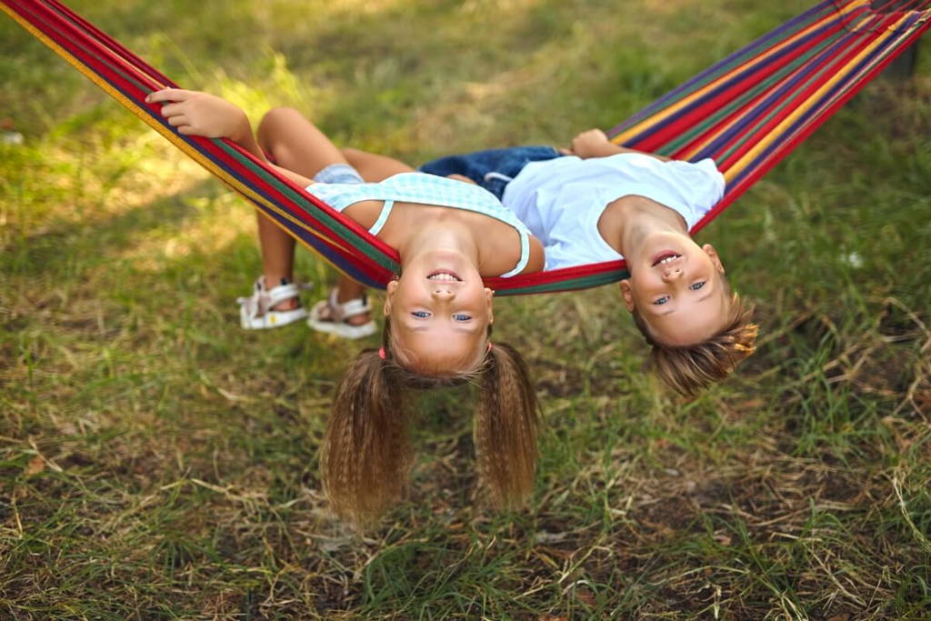 Brother and sister lying in a hammock.