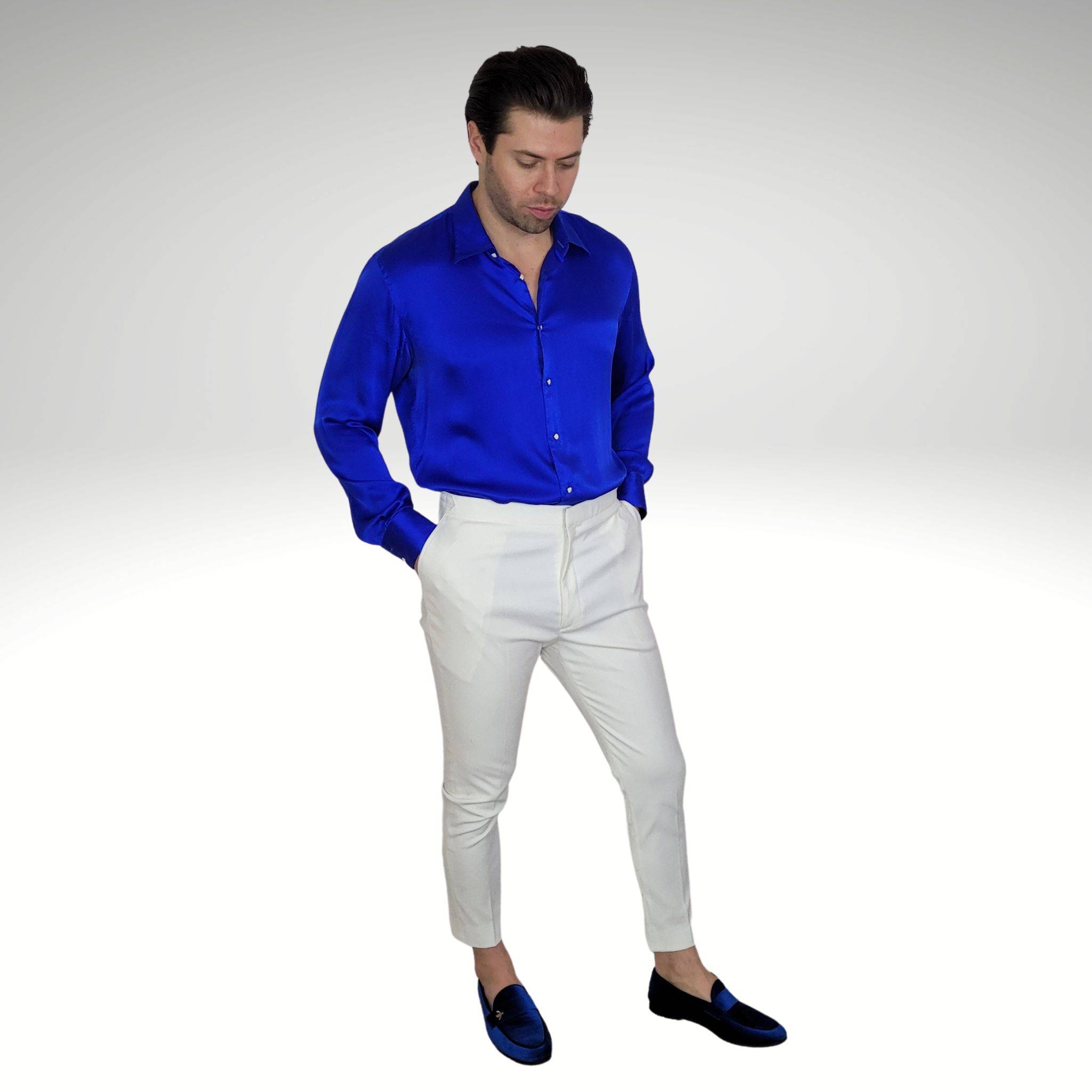 photo of a man wearing a blue silk shirt with white high waisted pants and blue velvet shoes