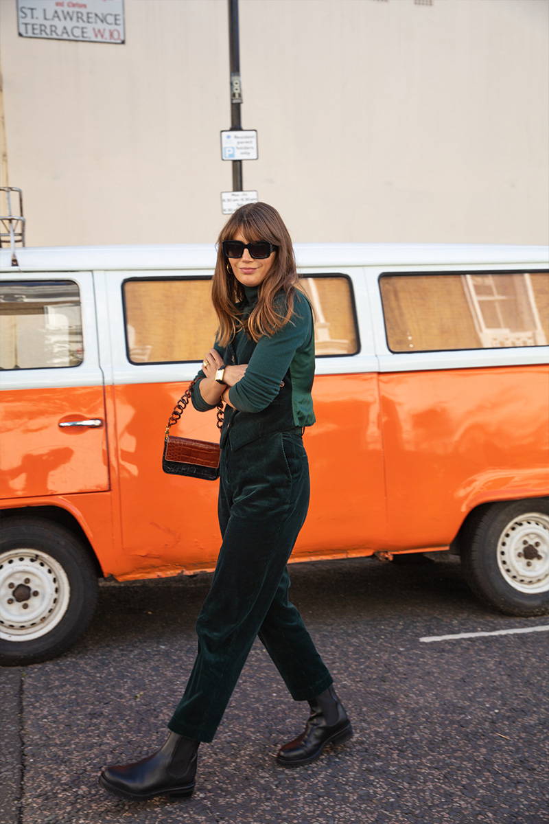 Sarah Corbett-Winder walks in front of a orange camper van wearing YOLKE's Corduroy Love Suit