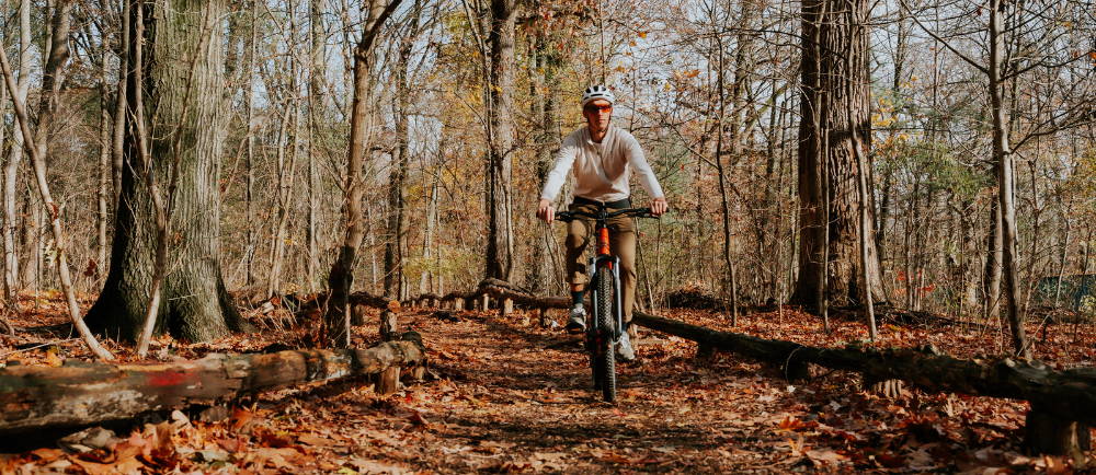 a man riding an electric mountain bike on a leaf covered trail in the woods