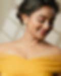 Smiling woman wearing an elegant gold necklace and matching earrings, captured in a warm, softly lit setting.