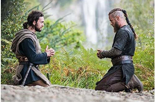 Ragnar and Athelstan, both kneeling and praying in nature with a waterfall behind the.