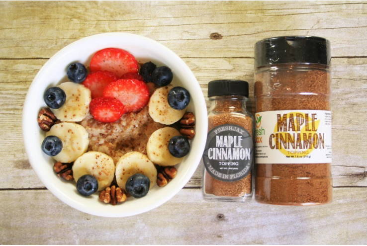 A bowl of Maple Cinnamon Oatmeal next to two bottles of FreshJax Organic Maple Cinnamon Topping.