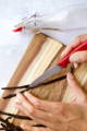 A person uses a paring knife to split vanilla beans down the middle on a wooden cutting board