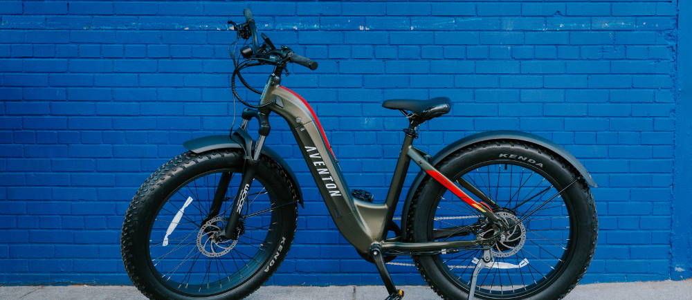 an aventon aventure fat tire bike in front of a blue brick wall