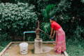 an image of a young woman working pumping a water tap to get clean water 