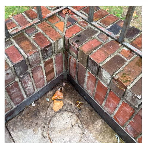 A weathered brick wall with white salt deposits, showing signs of efflorescence due to moisture damage.