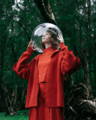 White female model covering her head with a giant transparent ball in a forest
