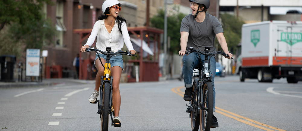 a woman and a woman riding ebikes on a quiet city street