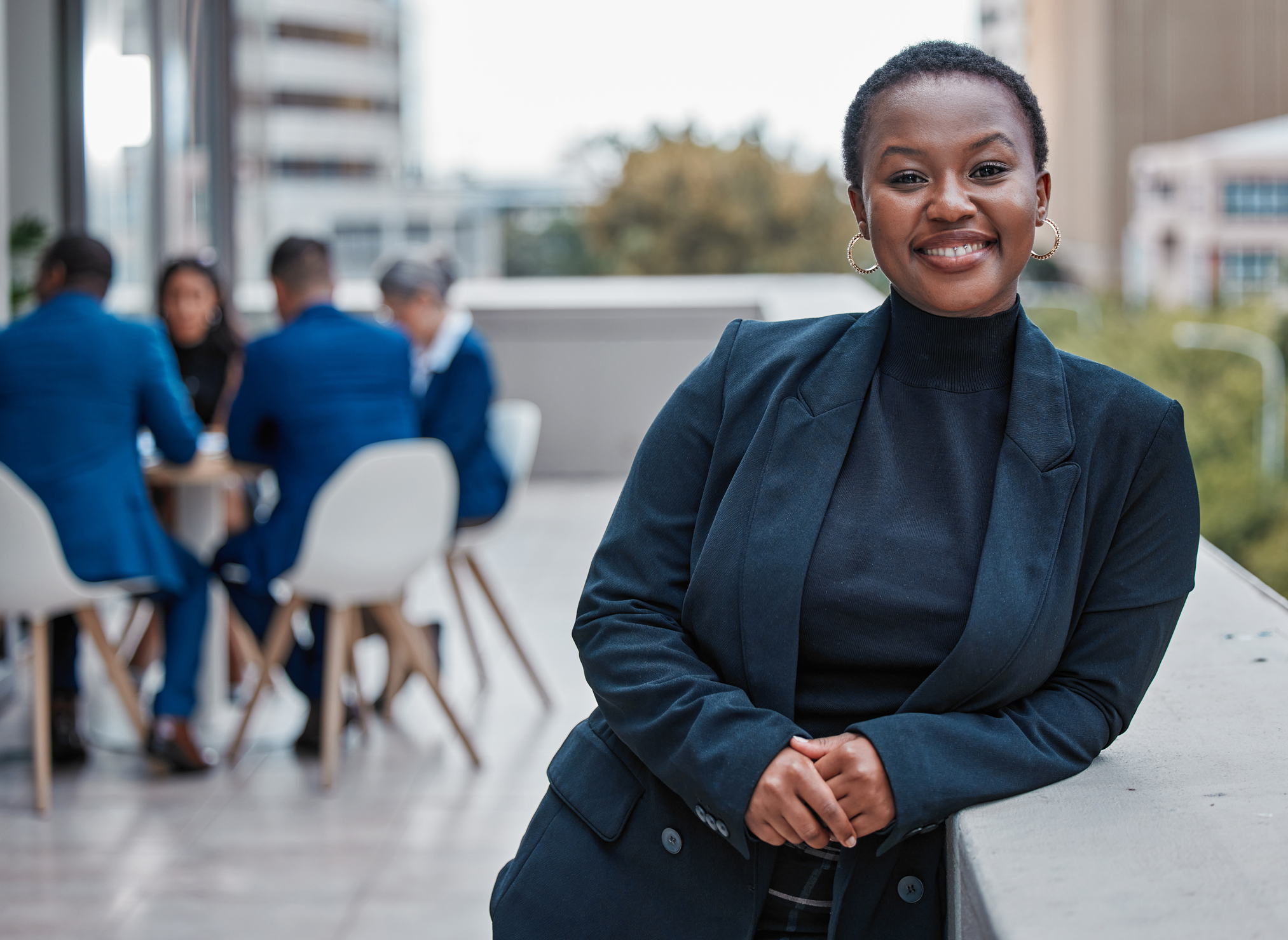 Cropped portrait of an attractive young businesswoman standing outside on the office balcony with her colleagues in the background