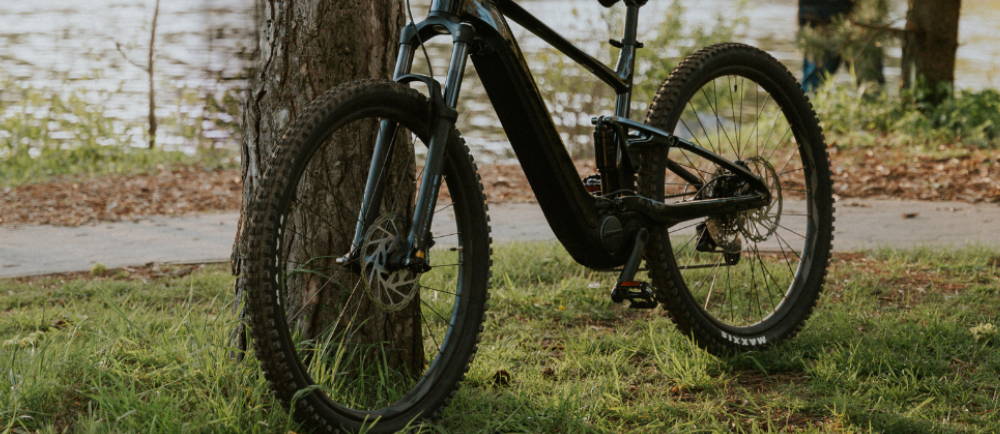 an electric mountain bike leaning against a tree