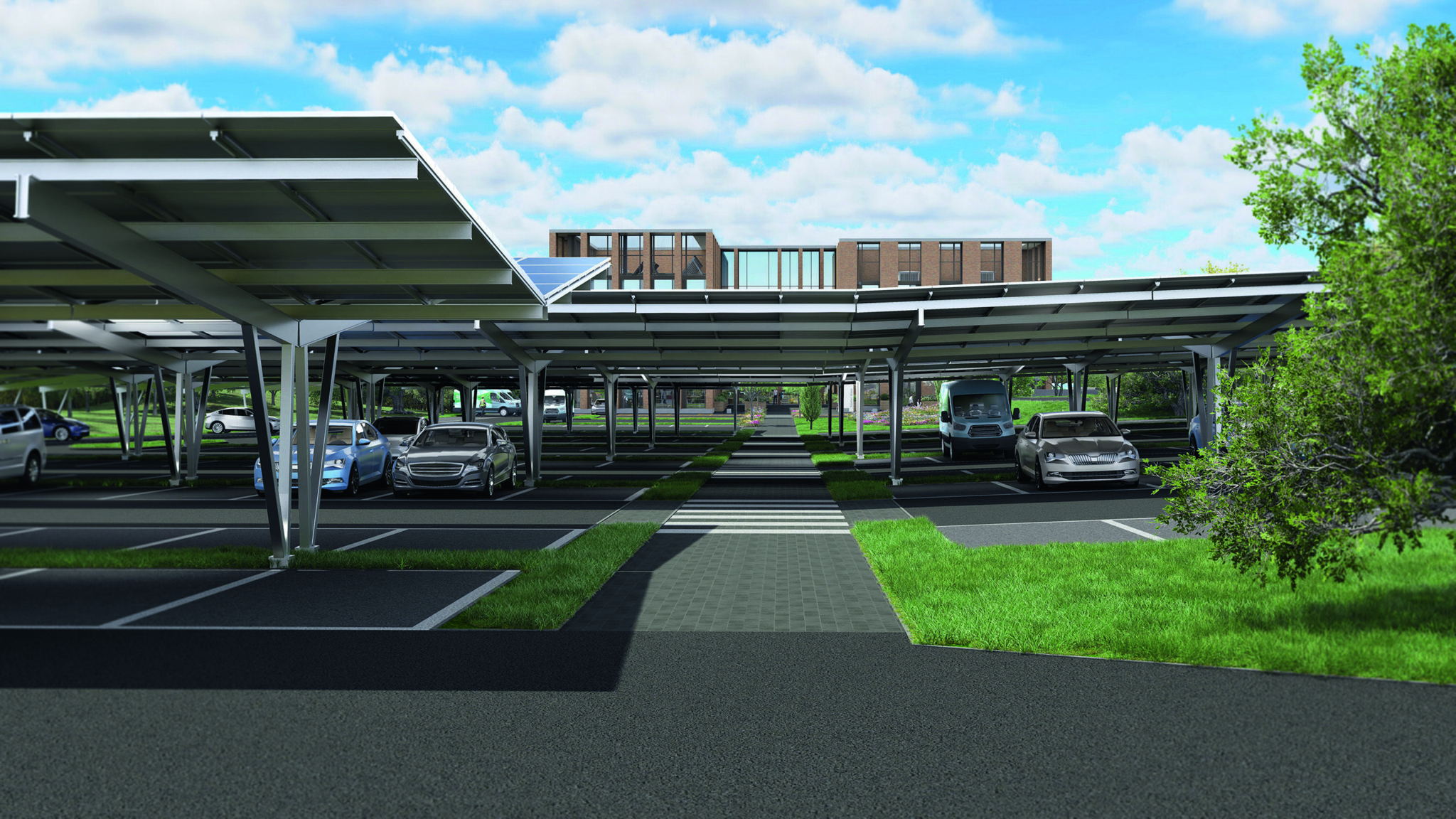 Covered parking lot with cars parked under solar panel canopies, green grassy areas between parking rows, trees on the right, and a modern brick building visible in the background under a partly cloudy sky.