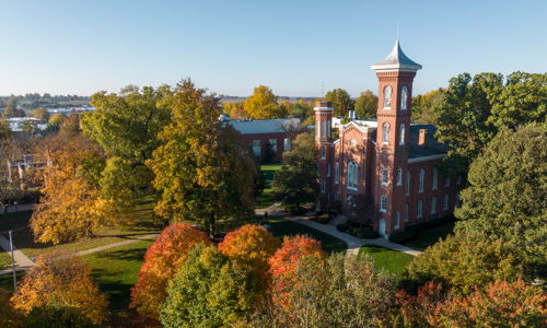 Charming school building surrounded by vibrant autumn foliage under a clear blue sky, evoking warmth and nostalgia.