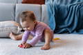 Baby girl grabbing a wooden toy on the floor. 