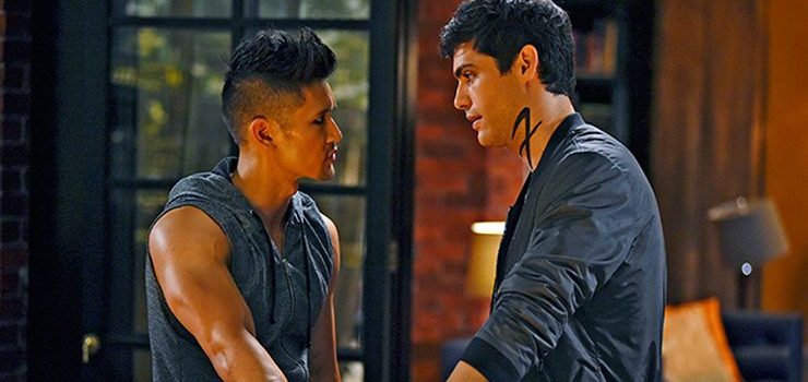 Magnus and Alec talking seriously and facing eachother waring dark clothing.