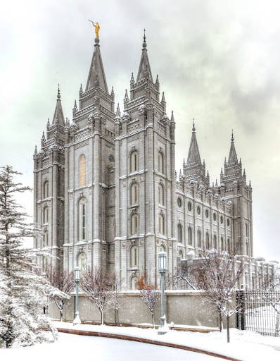 Angled Salt Lake Temple picture surrounded by snow and puffy clouds.