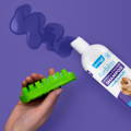 Furbliss shampoo bottle lying on its side beside a squirt of shampoo gel and a long hair dog brush.