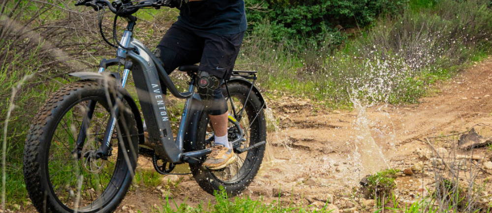 a man riding a fat tire Aventon Aventure electric bike through a puddle