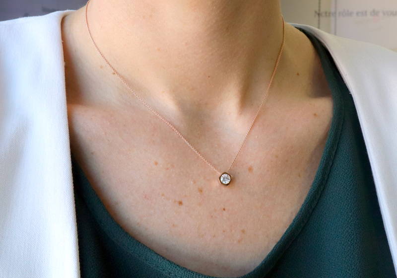 Pendentif avec centre de forme hexagonale avec diamant serti sur cou de femme.