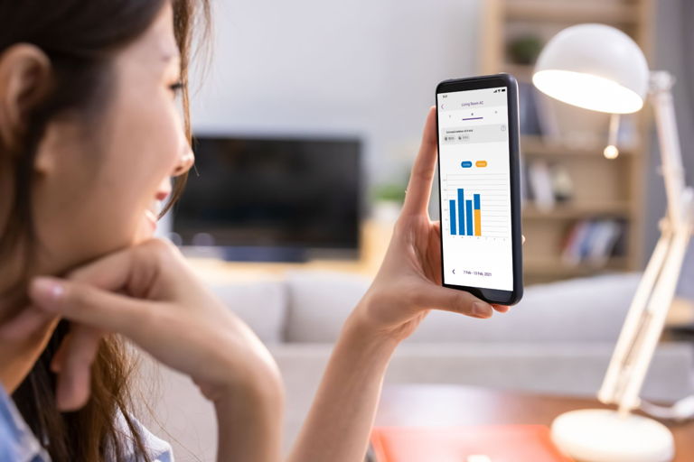 woman checking AC usage in Energy Insights smart AC control app feature