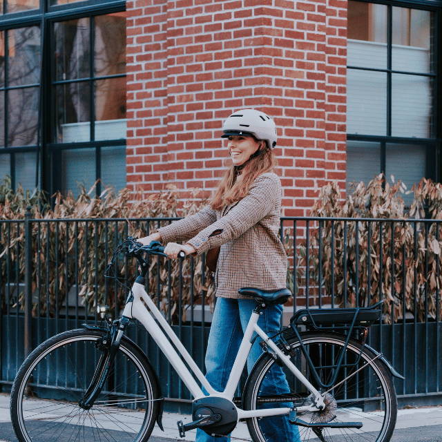 a woman standing next to a white electric city bike