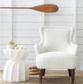 Image is of a white vintage style wing chair and a vintage stained oar.