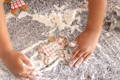 Child’s hands covered in flour while decorating gingerbread cookies on a kitchen counter during a hands-on baking activity