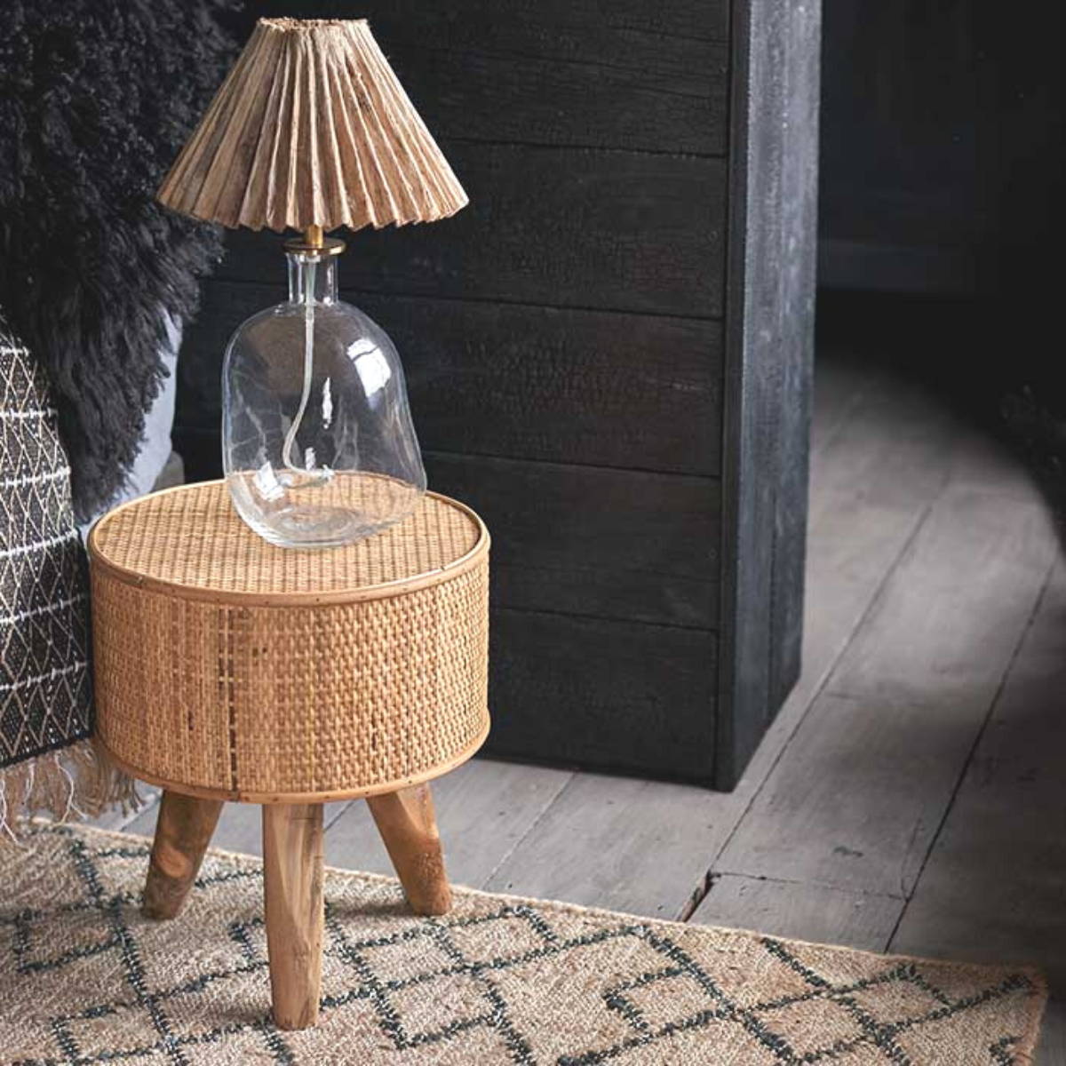 a small bedside table with a lamp made from glass with a brown pleated shade