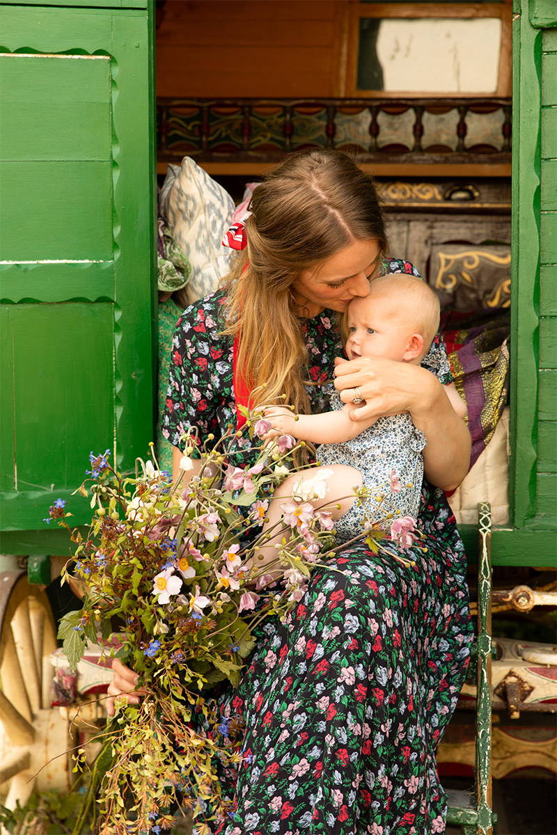 Tess Newall and her baby sit on the sets of her old  gypsy caravan 