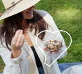 Woman smiling and enjoying som nuts from a plant based package enclosed in a heart