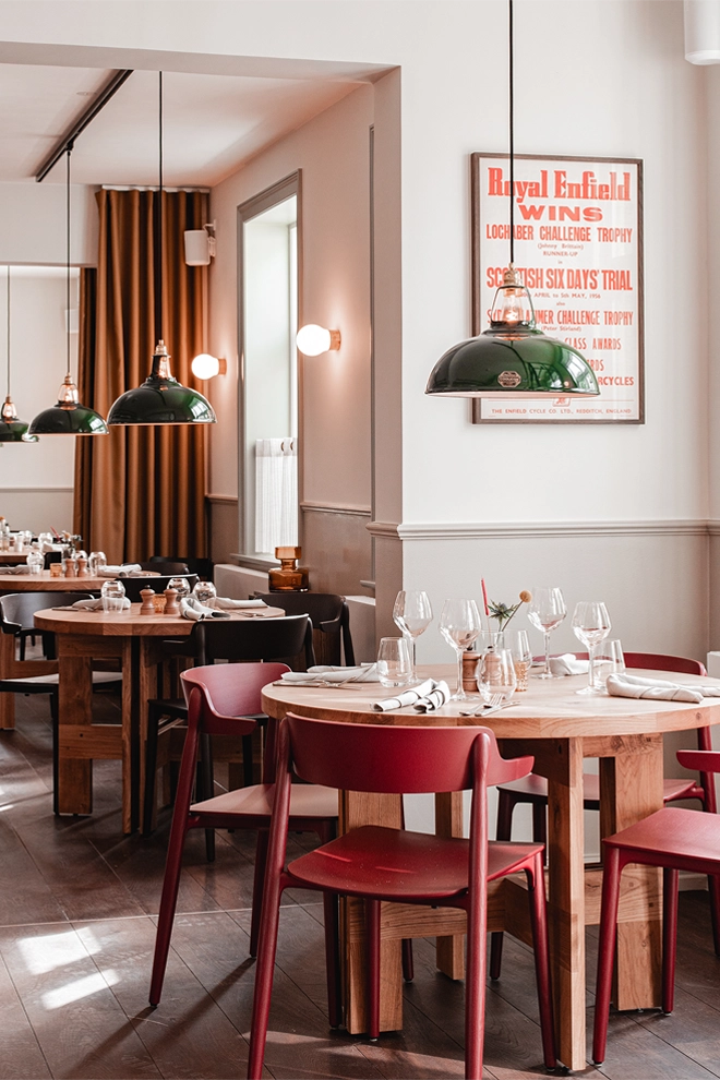 Large Green Coolicon Lampshades hanging low over wooden dining tables in a classic Danish Restaurant