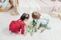 Brother and sister playing with colorful wooden toys in their playroom.