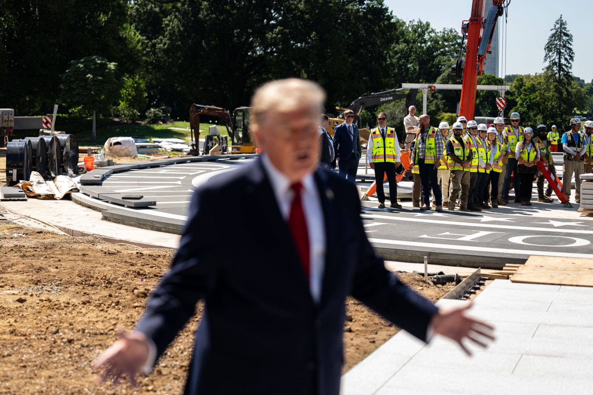 Blurred figure with open arms stands in front of construction workers