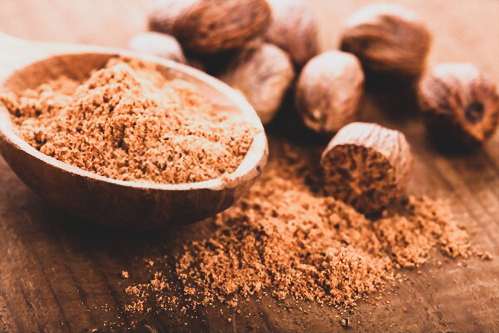 Nutmeg and powder in wooden bowl