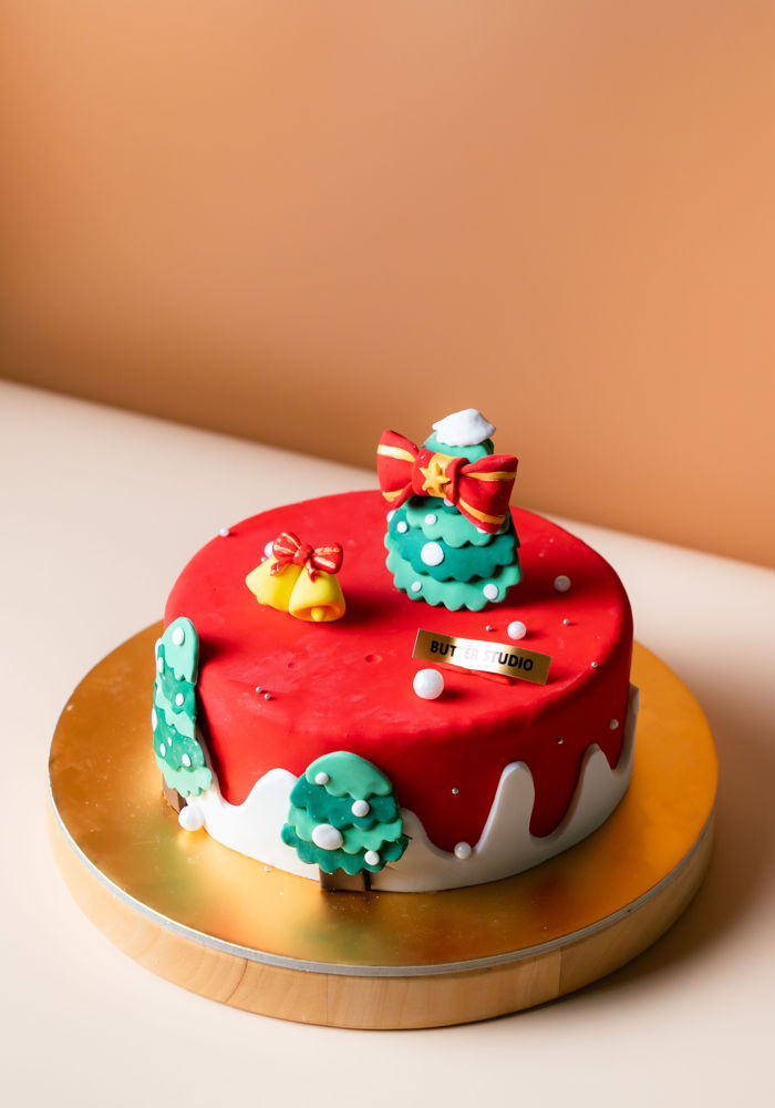 Merry Wonderland Christmas Cake in red cream with fondant Christmas trees and a holiday bow