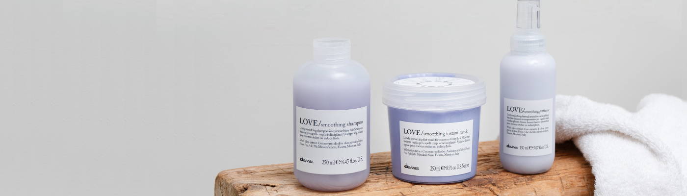 Davines LOVE Smoothing Shampoo, Instant Mask, and Perfector on a wooden bench