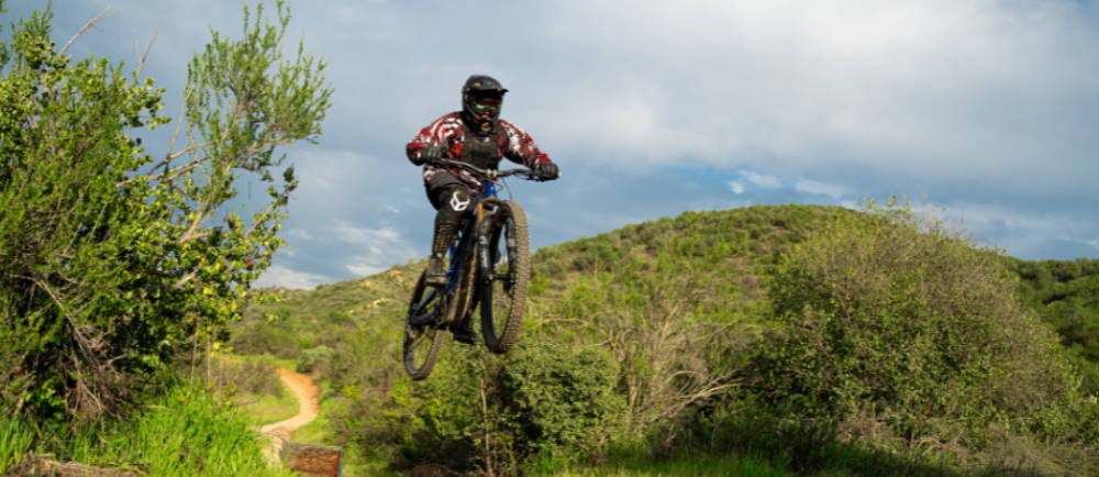 a person launching off a jump on a full suspension electric mountain bike