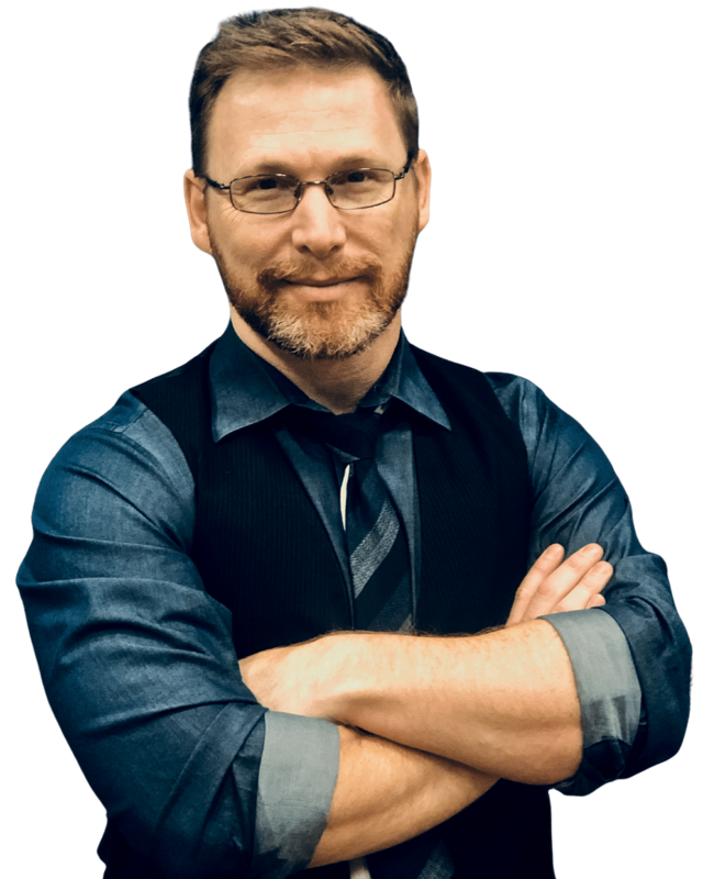 Confident man with short beard and glasses, wearing a blue shirt and vest, arms crossed.