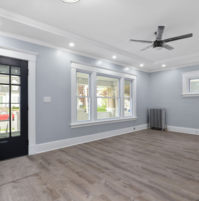 hardwood floored entrance foyer featuring natural light, a ceiling fan, and radiator