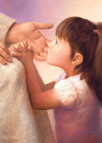 A little girl with brunette hair kneeling and praying at Jesus' knee.