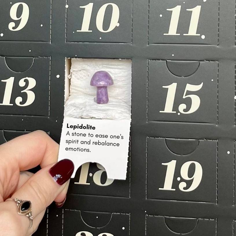 Opening day 4 of a crystal advent calendar to reveal a lepidolite mushroom carving