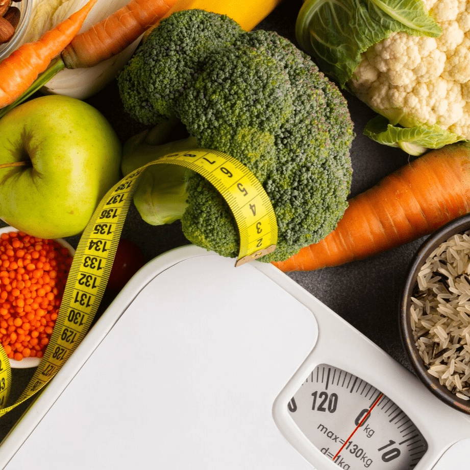 alimentos saludables al lado de una pesa corporal y elemento de medicion