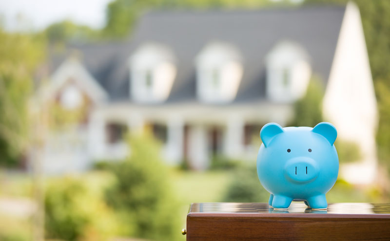 a little piggy bank laughs evilly in front of the house he is about to burn down