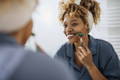 woman looking in the mirror using a face roller on her skin