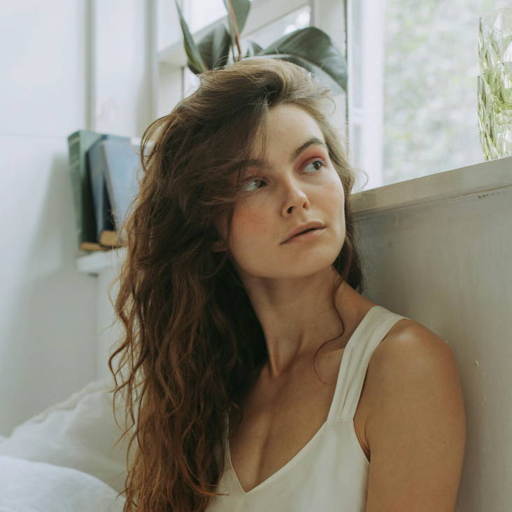 woman with long brown curls with a deep side part