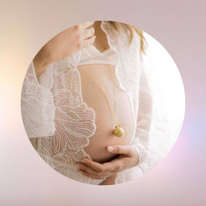 Femme enceinte portant un bola de grossesse HOKEE en pierre naturelle – bijou énergétique symbole d’amour, d’harmonie et de protection maternelle.