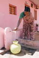 an image of a woman getting clean water from a tap outside of her home. 