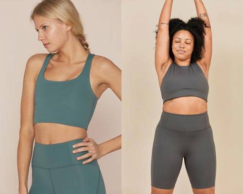 Woman wearing crop sports bra in turquoise with matching high waisted leggings and woman wearing grey crop sports bra and cycling shorts both from sustainable activewear brand Girlfriend Collective